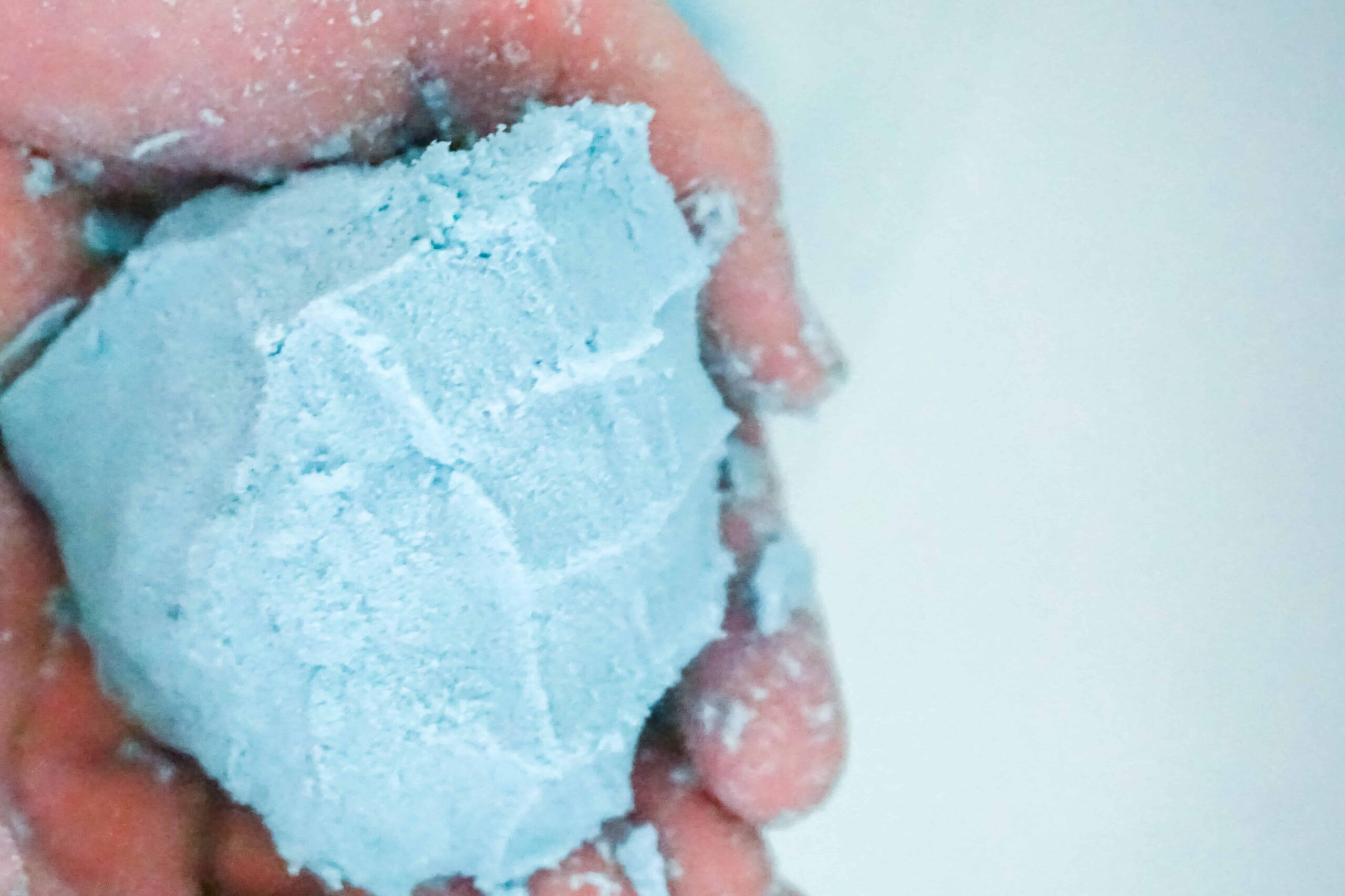 Child manipulating blue kinetic sand as a sensory support for focus