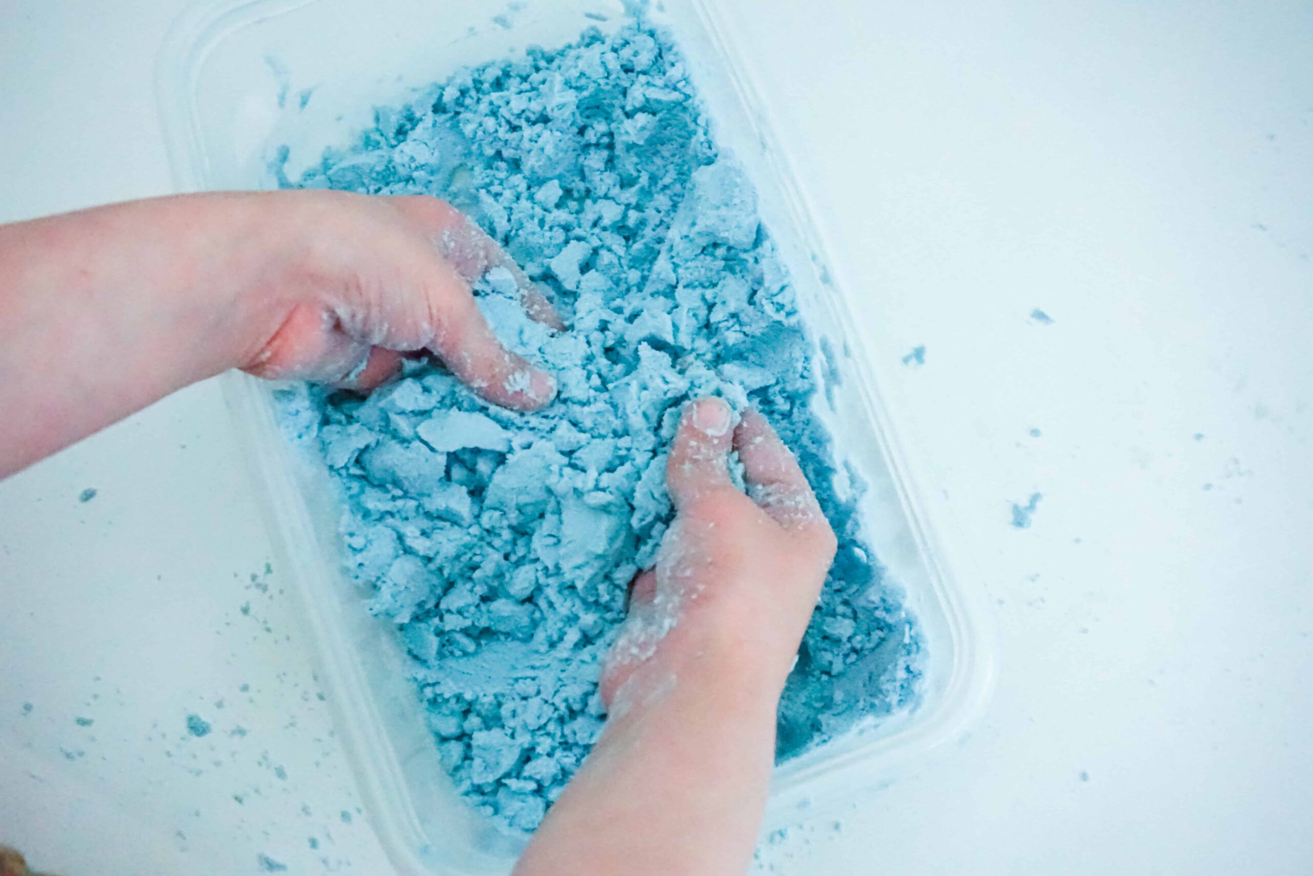 Hands using blue kinetic sand as a tactile sensory regulation tool