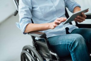 Woman in wheelchair using a digital touch screen tablet
