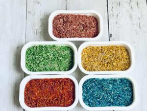 Four bowls of rainbow rice on a wooden table.