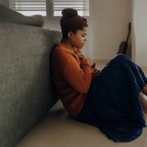 A woman sitting on the floor in a living room, utilizing 504 accommodations for anxiety.