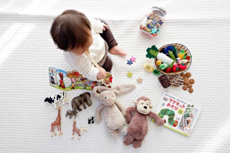 Baby on a blanket with a bunch of fine motor toys with them