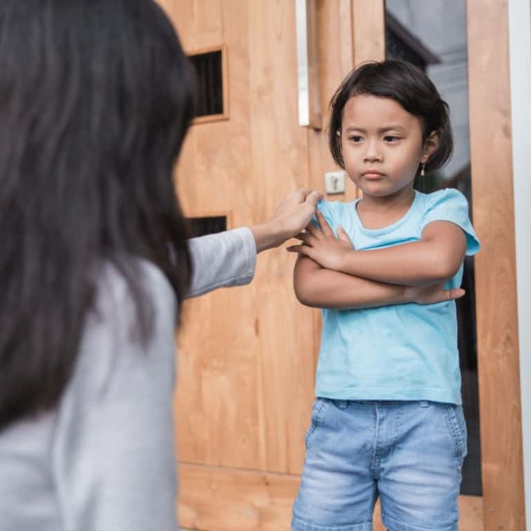 A woman discussing behavior with a little girl in front of a door, with the intention of setting iep goals.