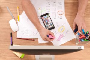 A person working on a computer with a cell phone and pens, focusing on executive functioning goals.