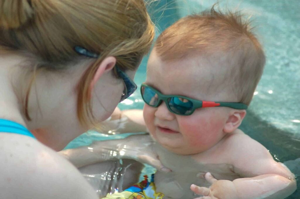 A woman demonstrating motor planning skills with a baby in a swimming pool.