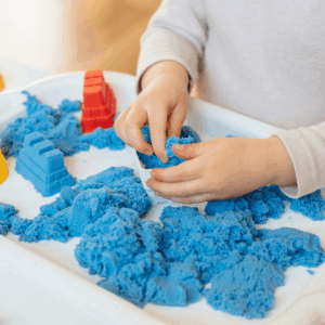 Child’s hands squeezing blue kinetic sand to provide calming tactile sensory input