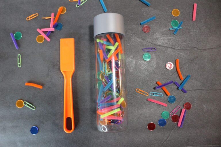 A bottle filled with colored pencils and a pencil sharpener.