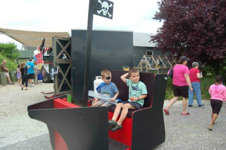 Two boys sitting on a small black and red pirate ship tuckerton seaport