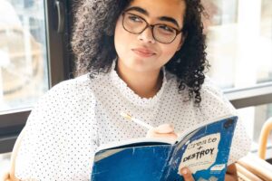 A young woman with glasses is reading a book, demonstrating inference skills.