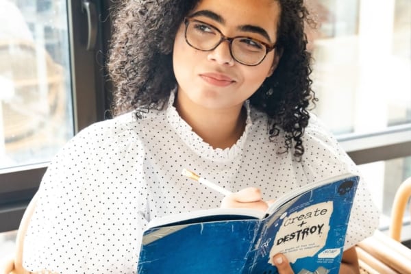 13 inference iep goals and objectives 4 A young woman with glasses is reading a book, demonstrating inference skills.