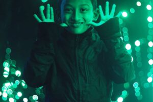 A young boy holding up his hands in front of glass.