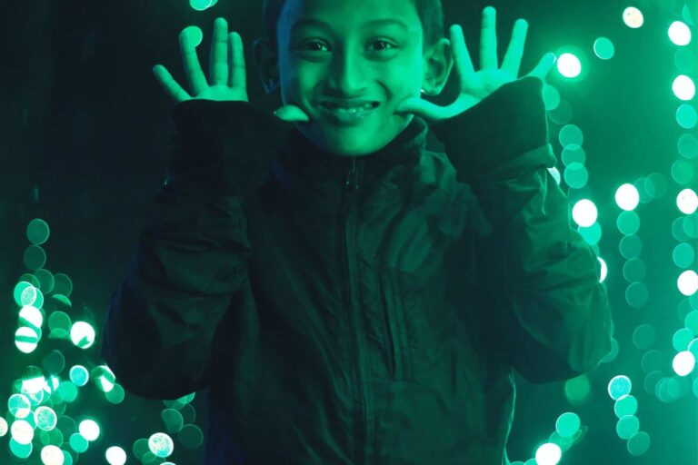 A young boy holding up his hands in front of glass.