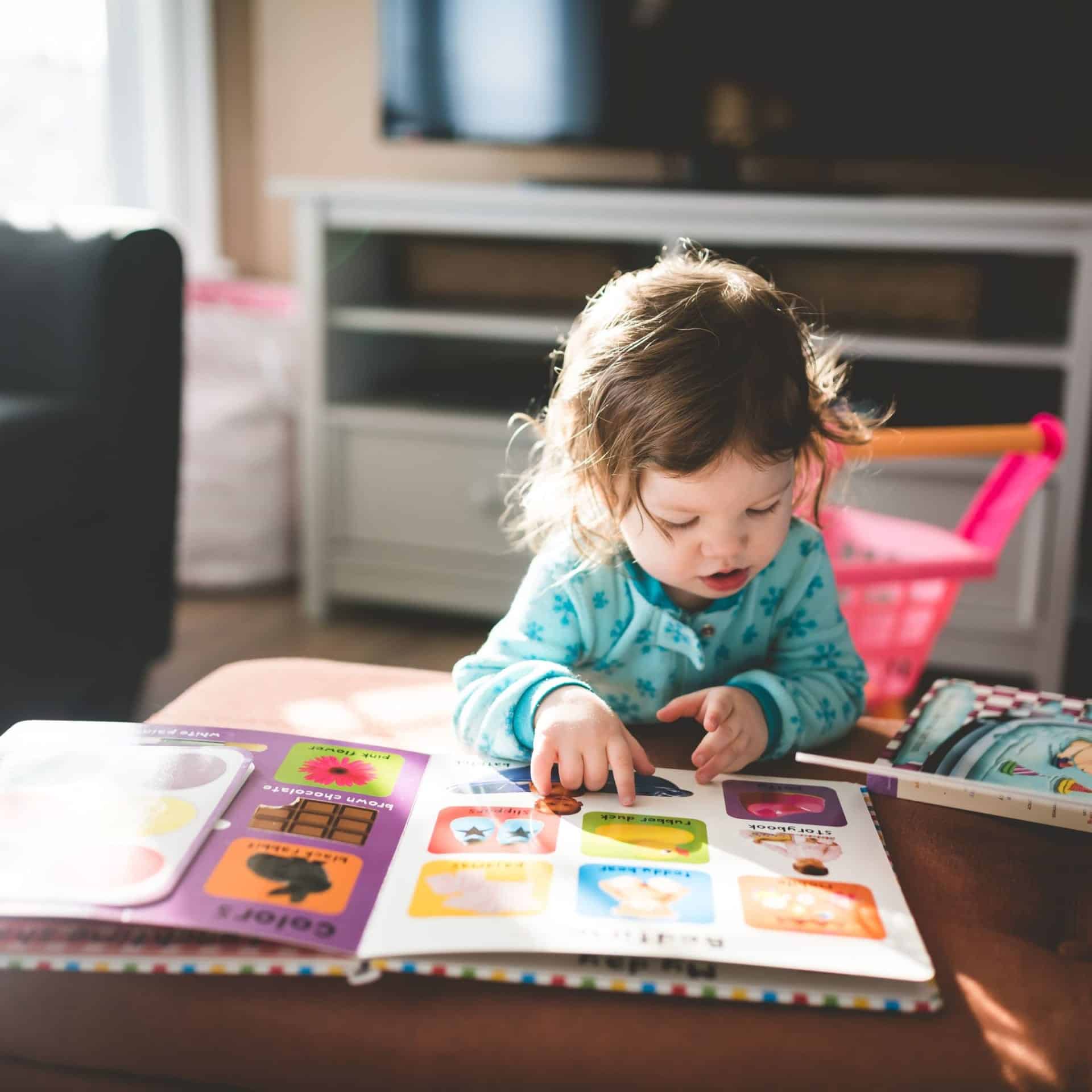 Toddler reading a book and working on her phonemic awareness skills